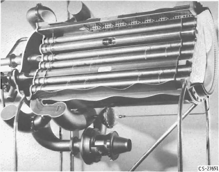 Photograph of a cutaway reactor model showing a row of long parallel tubes inside a cylindrical tank, with plumbing and a turbopump below